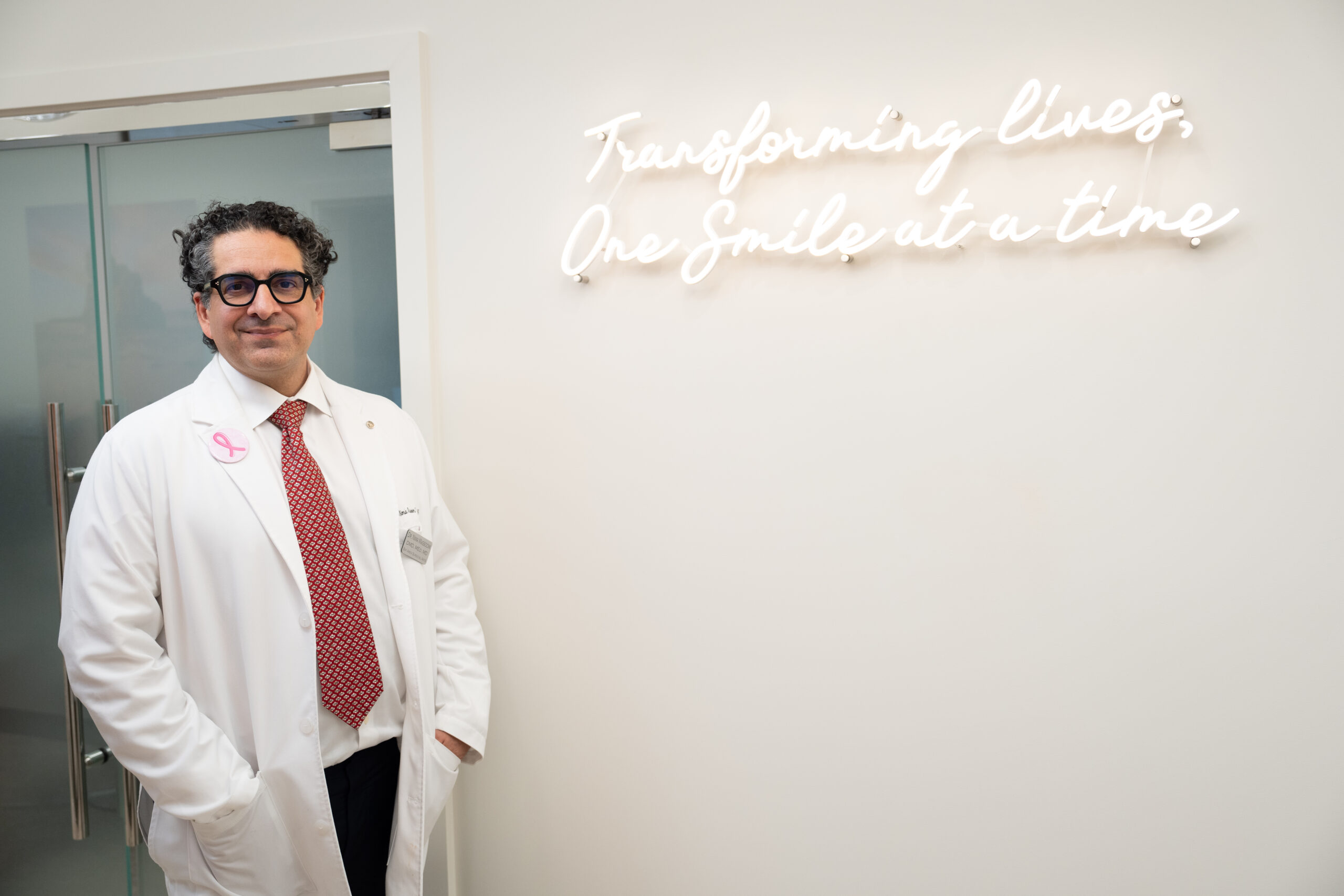 Dr Massoomi standing with a sign that reads "transforming lives"